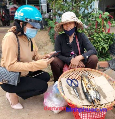 Ảnh Minh họa: Cán bộ Hội LHPN thị trấn Thanh Bình, huyện Bù Đốp hướng dẫn các chị em tiểu thương chợ Thanh Bình cài đặt phầm mềm Bluzone