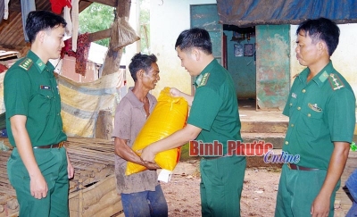 Cán bộ Đồn biên phòng cửa khẩu quốc tế Hoa Lư tặng gạo cho người nghèo  (Ảnh: Báo Bình Phước online)
