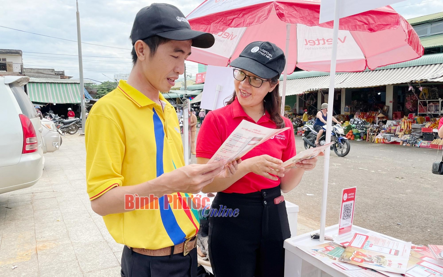Nhân viên Viettel Bình Phước hướng dẫn người dân  cài đặt ứng dụng thanh toán không dùng tiền mặt (Ảnh: Báo Bình Phước Online)