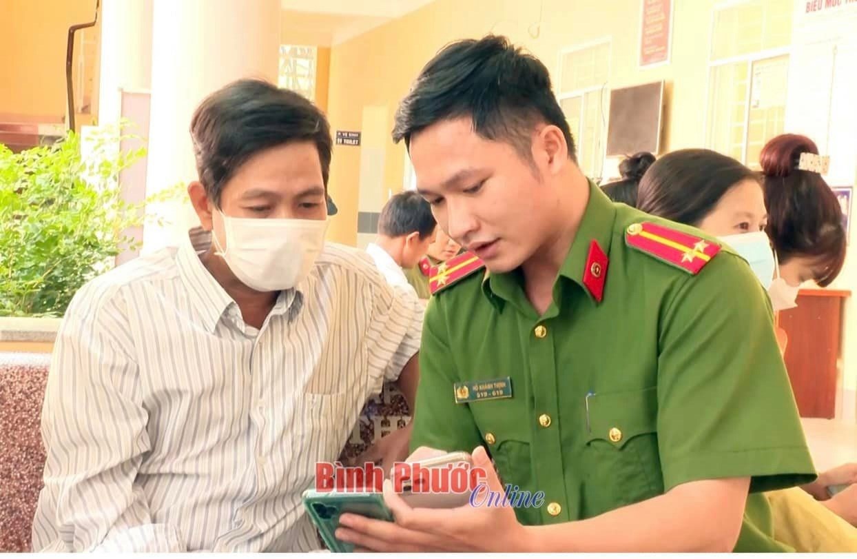 Cán bộ, chiến sĩ Công an thị xã Chơn Thành hướng dẫn người dân cài đặt ứng dụng định danh điện tử VneID (Nguồn ảnh: Báo Bình Phước Online)